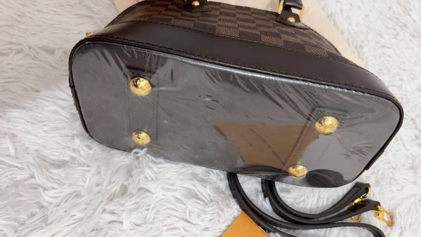 Bottom view of the Louis Vuitton-style Alma replica bag showing protective gold feet and leather finish Bottom view of the Louis Vuitton-style Alma replica bag showing protective gold feet and leather finish