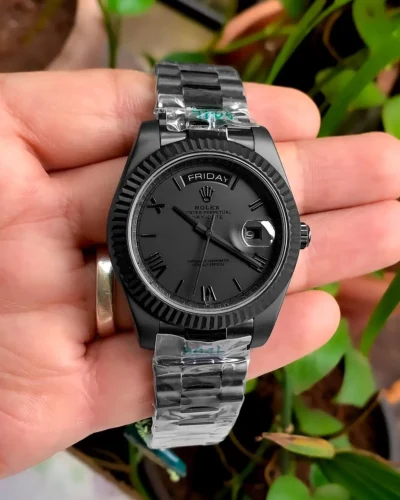 Full black Rolex Day-Date watch 41mm with Roman dial held in hand