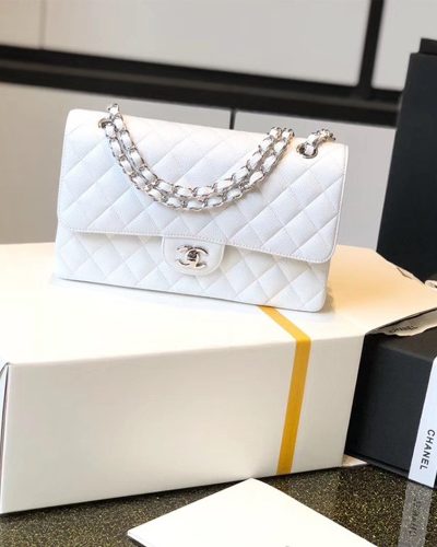 White Chanel classic flap bag with silver chain resting on its box